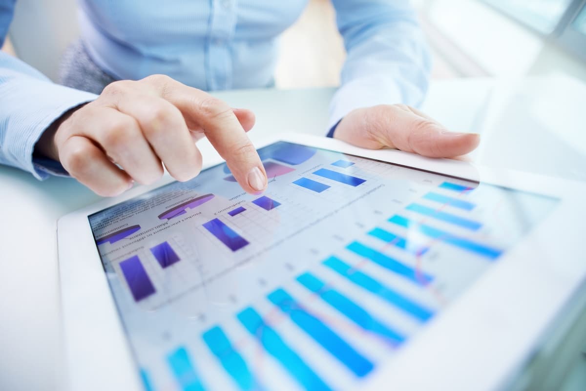 woman holding tablet reviewing bar graph reporting data